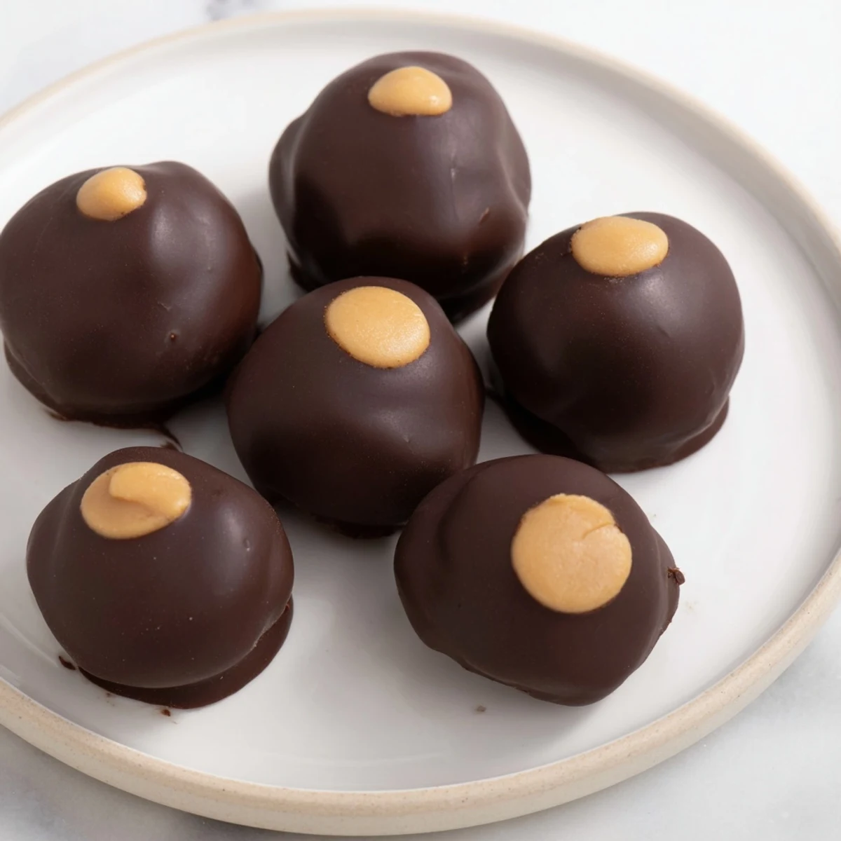 Creamy homemade peanut butter balls, coated in glistening chocolate, ready for enjoying.