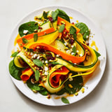 Freshly assembled Pistachio and Cranberry layered salad featuring a rainbow of vegetable ribbons with crunchy toppings.