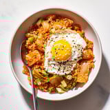 Colorful Kimchi Fried Rice in a rustic bowl, featuring vibrant orange carrots, green onions, and caramelized kimchi, ready for a quick weeknight meal.  