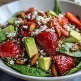 Colorful strawberry avocado quinoa salad featuring creamy avocado, juicy berries, and toasted almonds on a rustic table.  