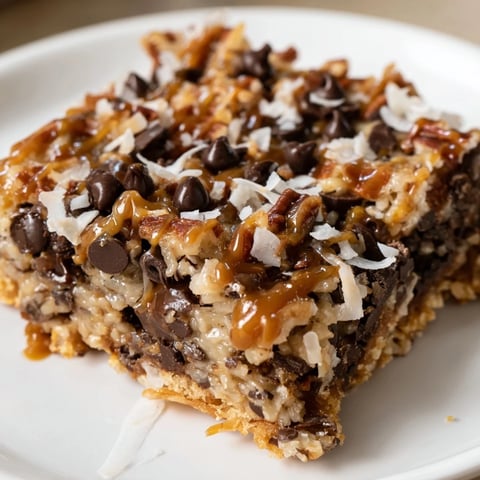 Warm, gooey 7-Layer Magic Bars drizzled with salted caramel, a perfect sweet treat.