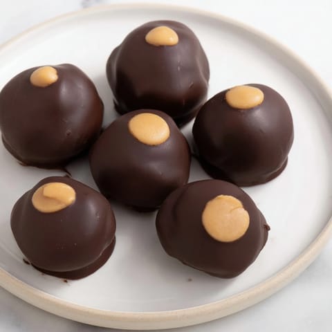 Creamy homemade peanut butter balls, coated in glistening chocolate, ready for enjoying.