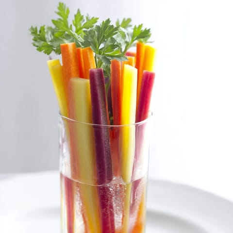 Vibrant Simple Crudités arrangement of chilled carrot sticks in tall glasses make a colorful appetizer.