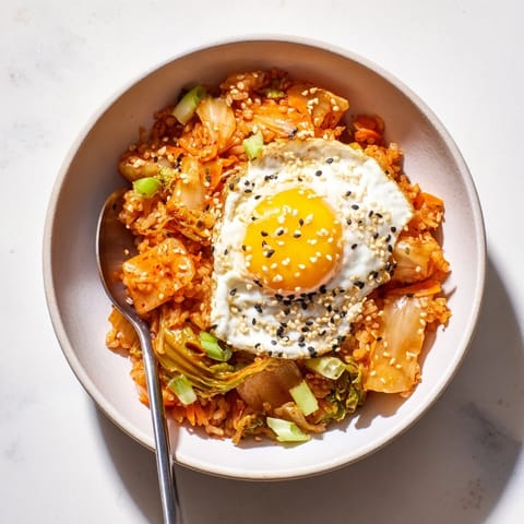 Colorful Kimchi Fried Rice in a rustic bowl, featuring vibrant orange carrots, green onions, and caramelized kimchi, ready for a quick weeknight meal.  