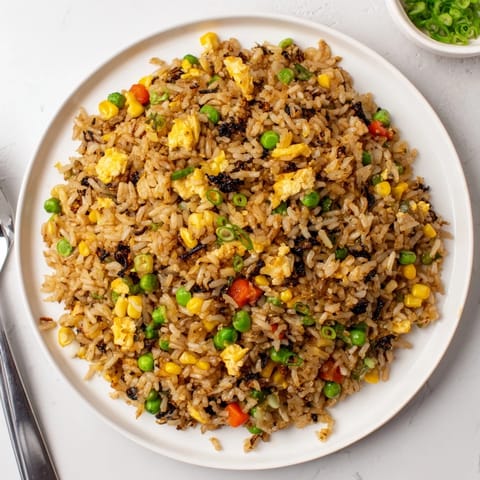 In a hot wok, a chef tosses the umami-rich Black Garlic Fried Rice, sending aromatic steam and sesame oil scents upward.  