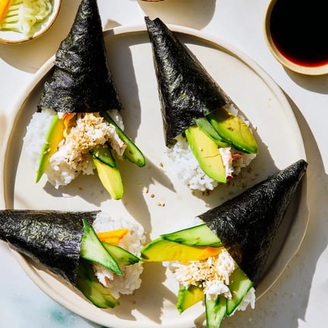 Sushi Rice Hand Rolls featuring flaky crab and sticky sushi rice, served with soy sauce and pickled ginger.