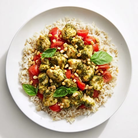 Savory, herb-packed Chicken Pesto Rice Bowl with golden chicken pieces nestled on fluffy rice and fresh tomato chunks for brightness.