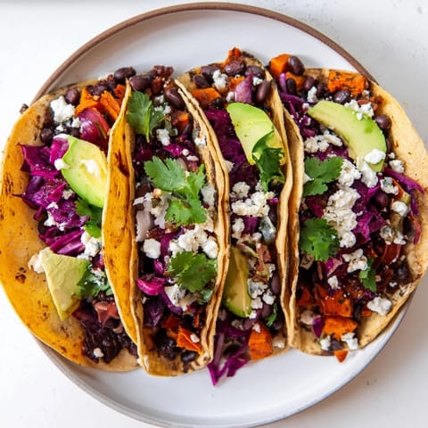 Savory roasted sweet potatoes and black beans fill these Black Bean and Sweet Potato Tacos, topped with creamy avocado and cilantro.