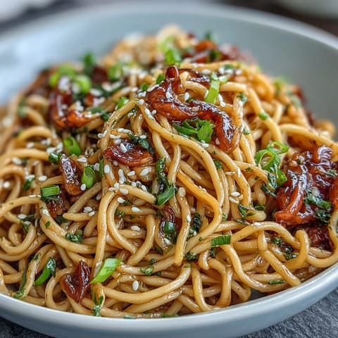 Savory soy-glazed noodles tossed with fresh ginger, scallions, and garlic, served hot for a quick and flavorful dinner.