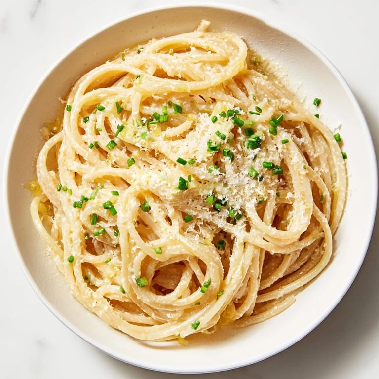 A close-up of steaming miso butter pasta served, showcasing the savory sauce and fresh chives sprinkled on top.