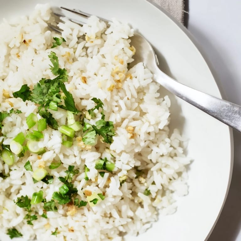Fluffy jasmine rice garlic side dish topped with fresh cilantro, steaming warmly on a rustic plate.