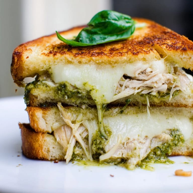 Freshly cooked Mozzarella Pesto Chicken Grilled Cheese, featuring melted mozzarella, vibrant pesto, and tender shredded chicken on sourdough.