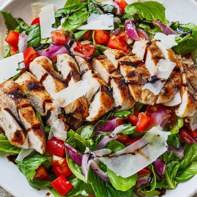 Enjoy a light Italian-American dinner with this colorful Bruschetta Chicken Salad, featuring tender chicken, fresh basil, and shaved Parmesan on mixed greens.