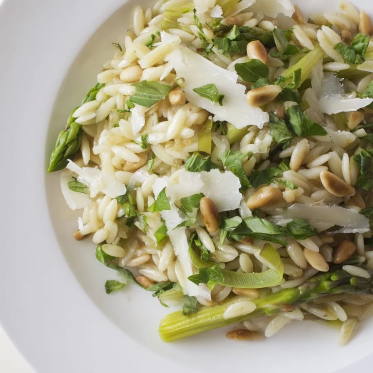 A beautiful bowl of chilled Asparagus Lemon Orzo Salad features tender pasta, crisp green asparagus, and fresh herbs, ready for a sunny spring lunch.  