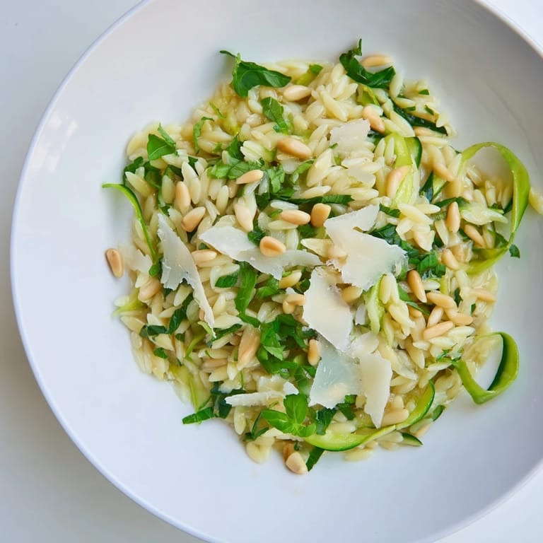 Serving suggestion for Asparagus Lemon Orzo Salad: a light vegetarian dish with orzo, shaved asparagus, lemon zest, and grated Parmesan on a rustic table.