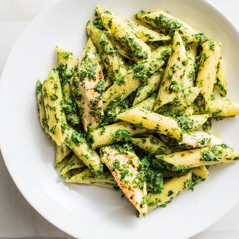 A fork twirls herby Chimichurri Chicken Pasta beside lemon wedges, ready for a zesty, dairy-free dinner.