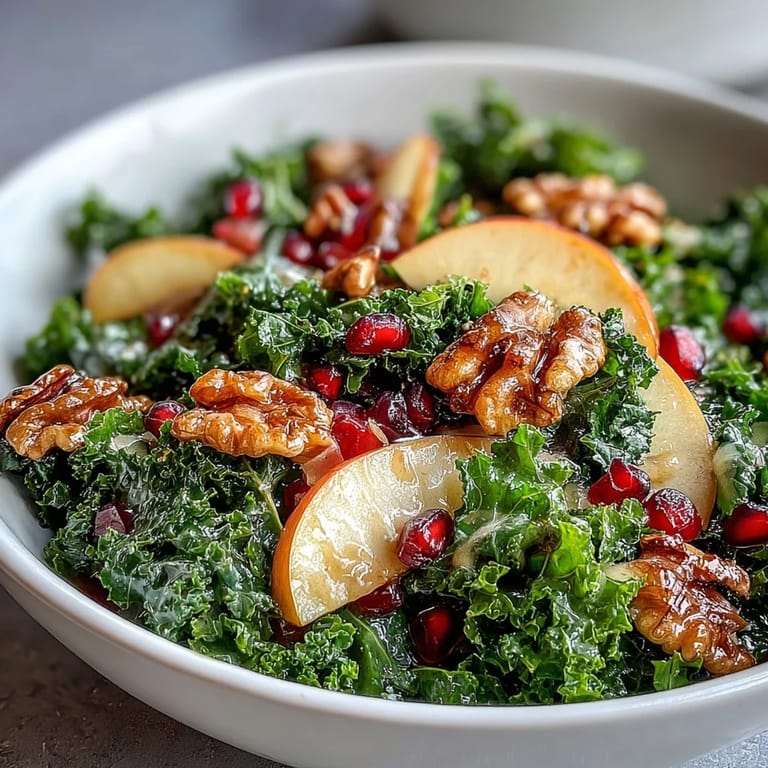 Close-up of a hearty Kale and Pomegranate Bowl, showing tender greens mixed with sweet apple and ruby-red seeds for a refreshing salad.