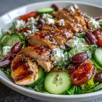 Grilled chicken breast slices atop a colorful Greek salad with crisp romaine, juicy tomatoes, and tangy feta cheese.  